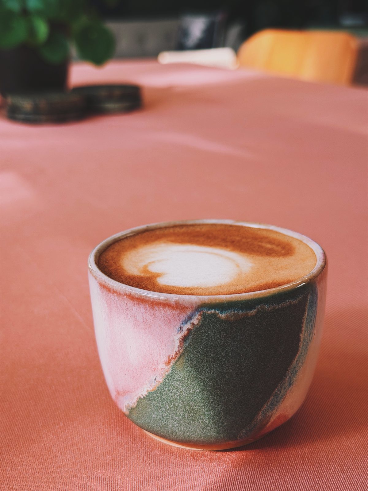 Cappuccino in een handgemaakt kopje met roze en groen glazuur