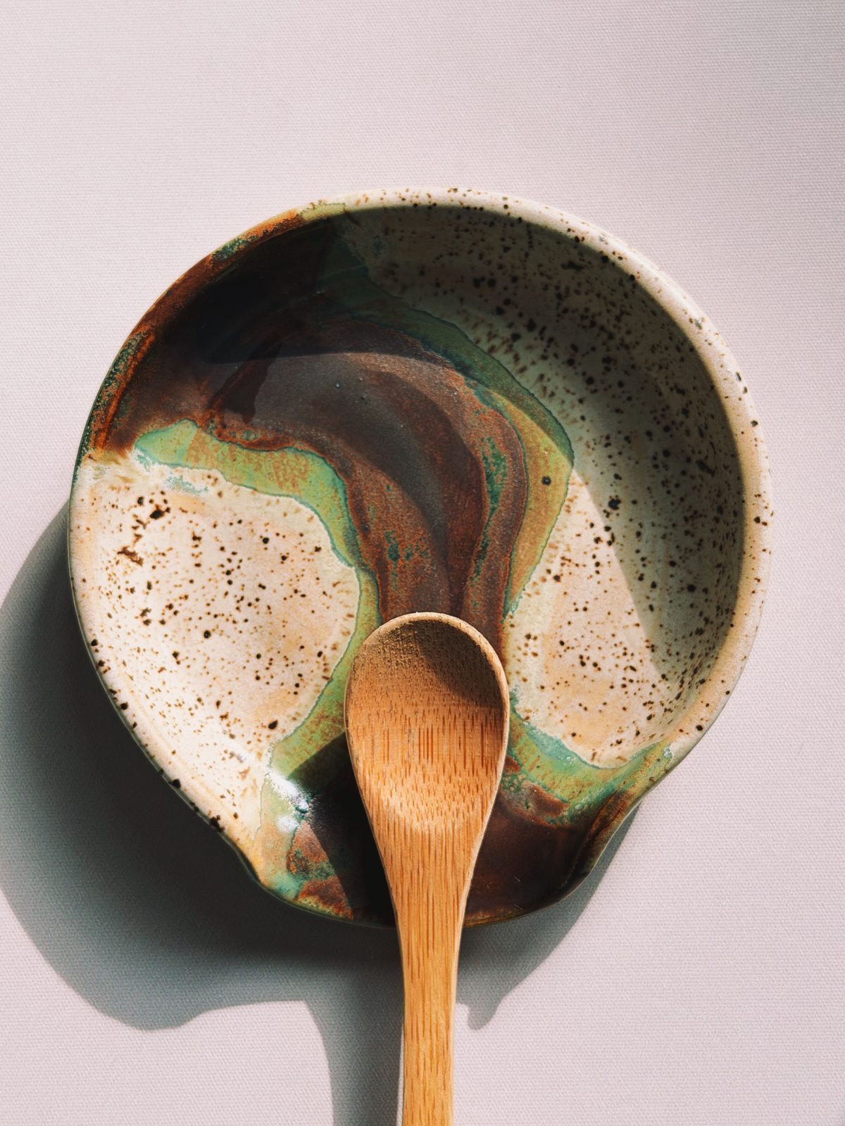 Gespikkelde kom met groen en bruin glazuur en een houten lepeltje