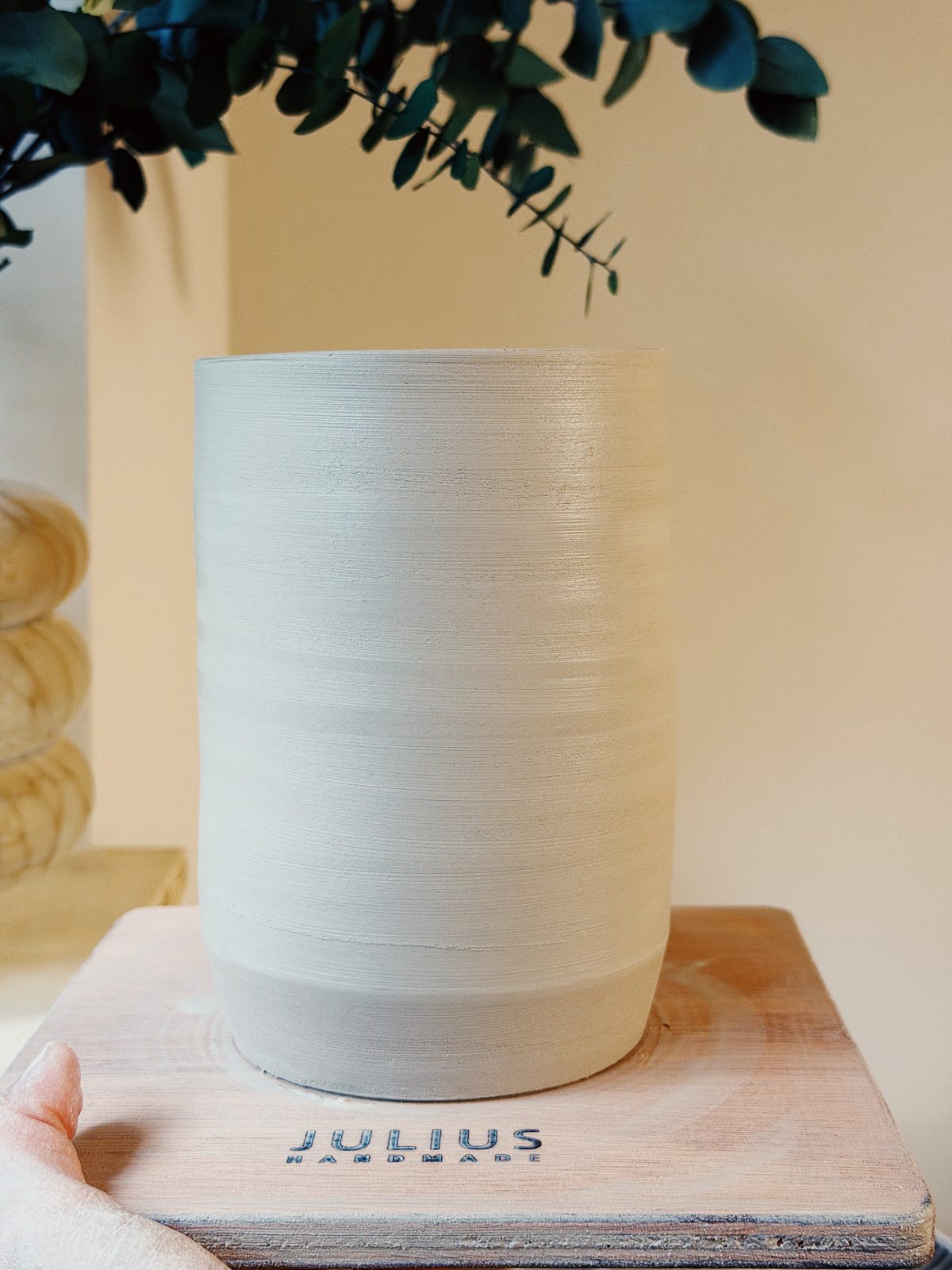 Hoge witte vaas met draairillen naast eucalyptus